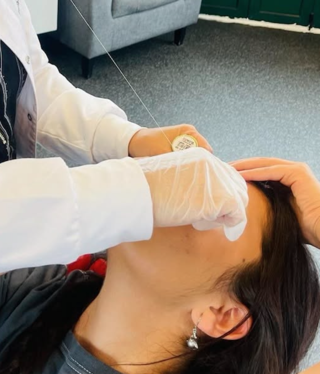 Eyebrow threading being performed at Eyebrow Threading & Beauty — precise technique, gloved hands, cotton thread